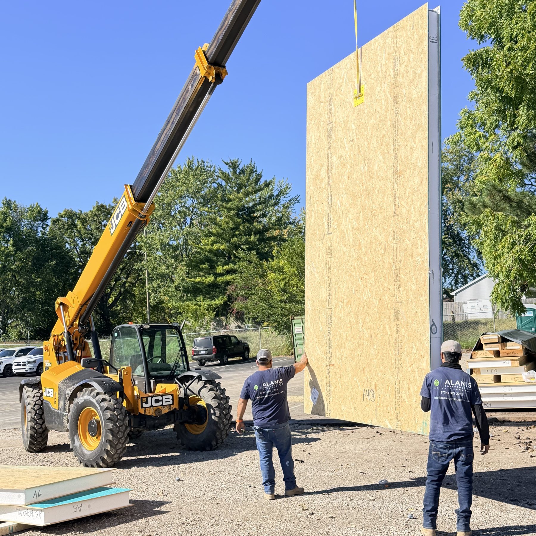 Alanis crew setting a SIP wall panel with a telehandler